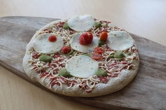 an unbaked frozen pizza on a wooden plank