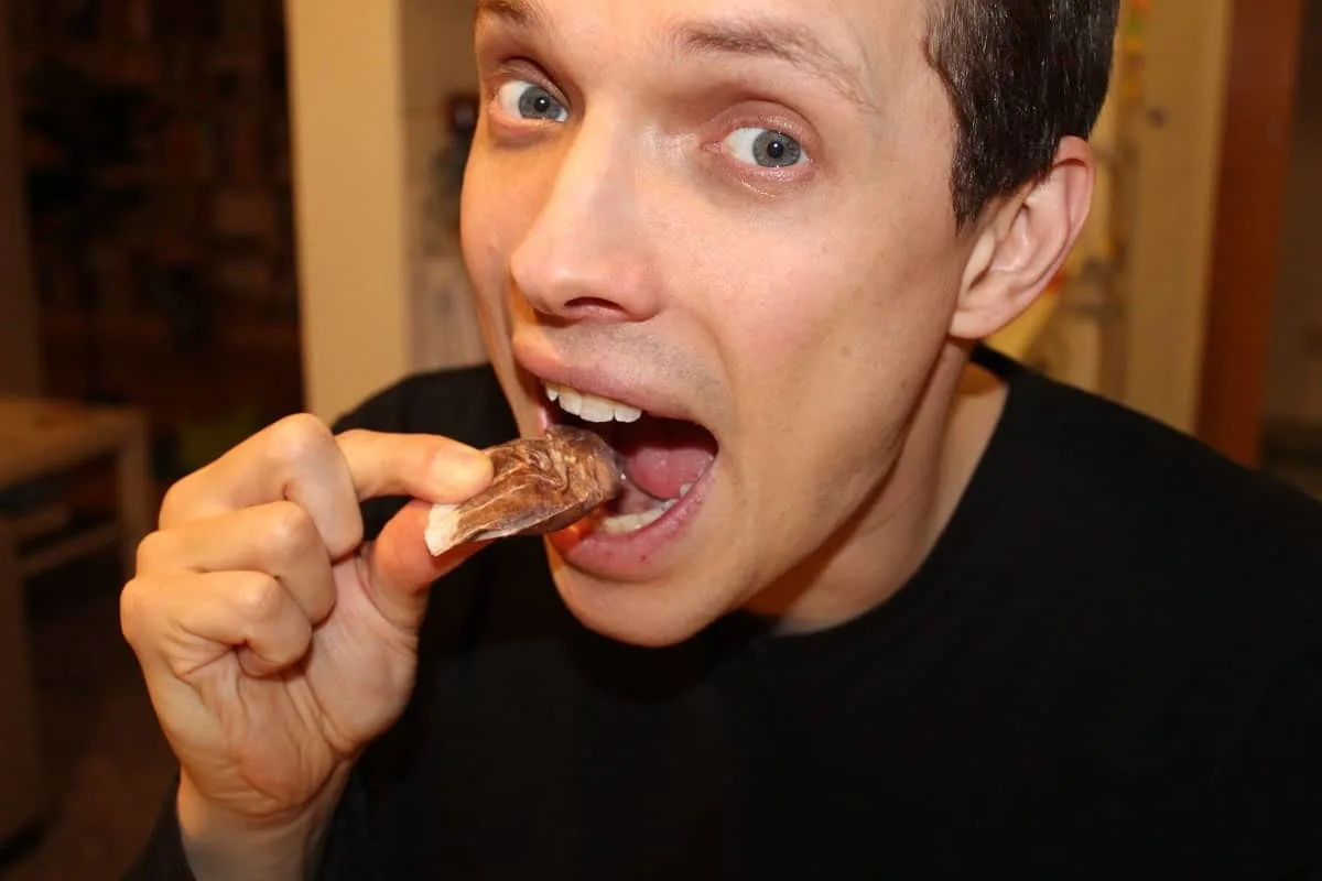 a guy in his kitchen about to eat an empty paper muffin wrapper