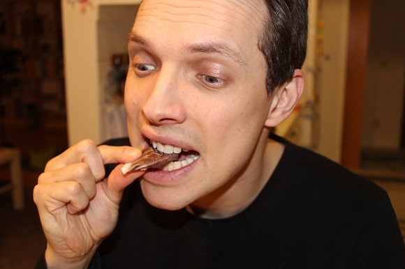 a guy eating and tasting a paper muffin wrapper