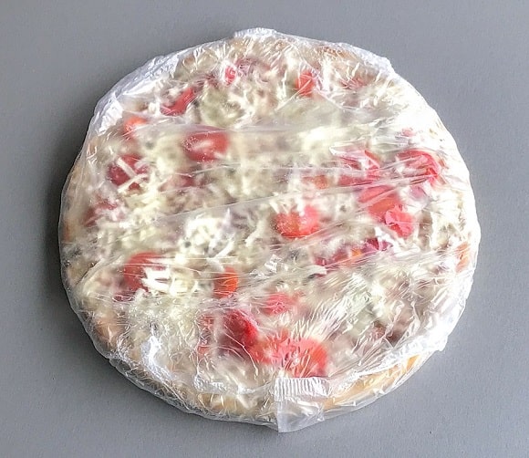 a frozen pizza in its plastic packaging