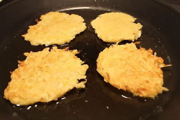 four hash browns frying in olive oil