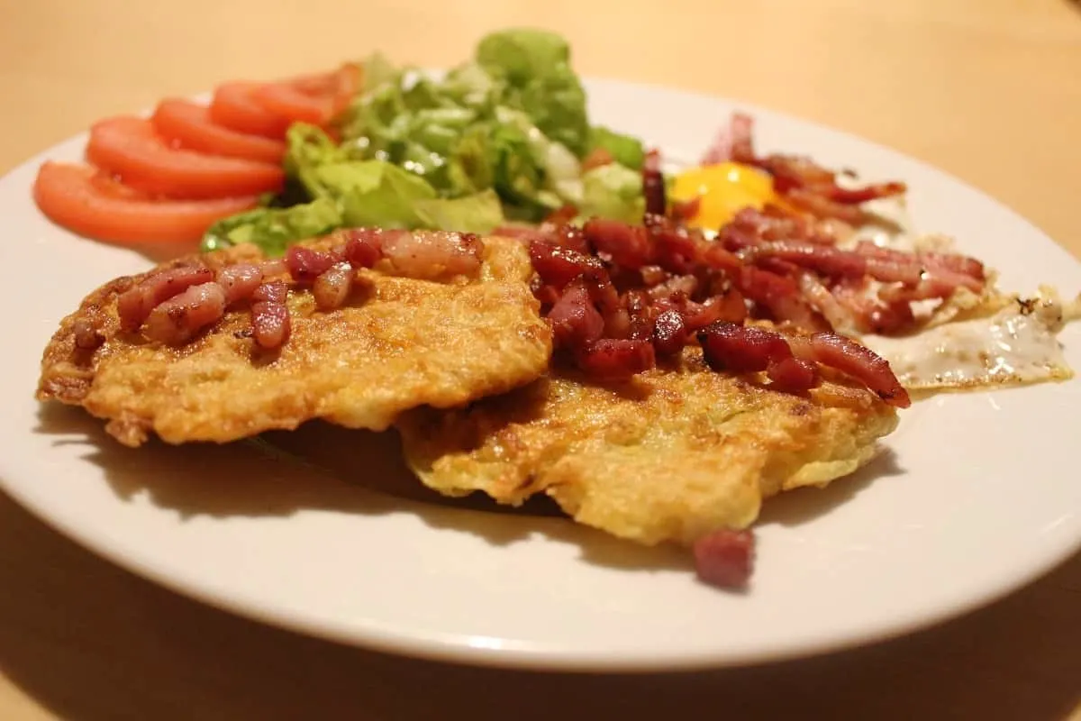 two homemade hash browns with bacon, eggs, and vegetables on a plate