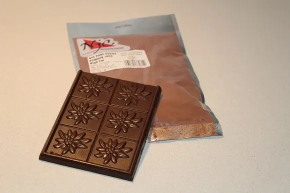 a bag of pure cocoa powder and a bar of bittersweet dark chocolate