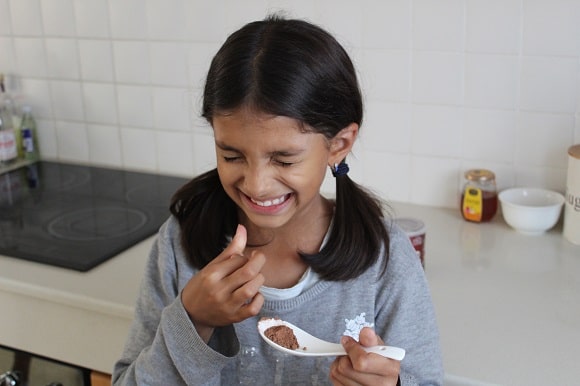 a little girl tasting bitter cocoa powder