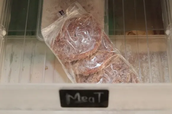 four frozen hamburger patties in a sealed freezer bag in the freezer