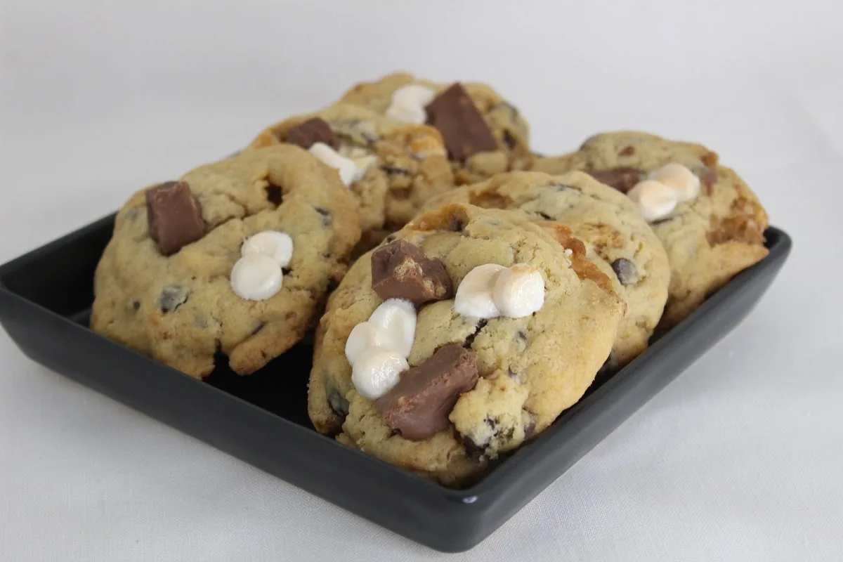 a small black plate with six delicious S'mores cookies on it