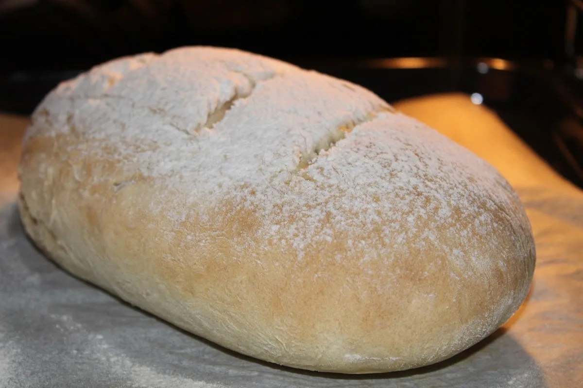 a bread loaf with flour on top baking in the oven