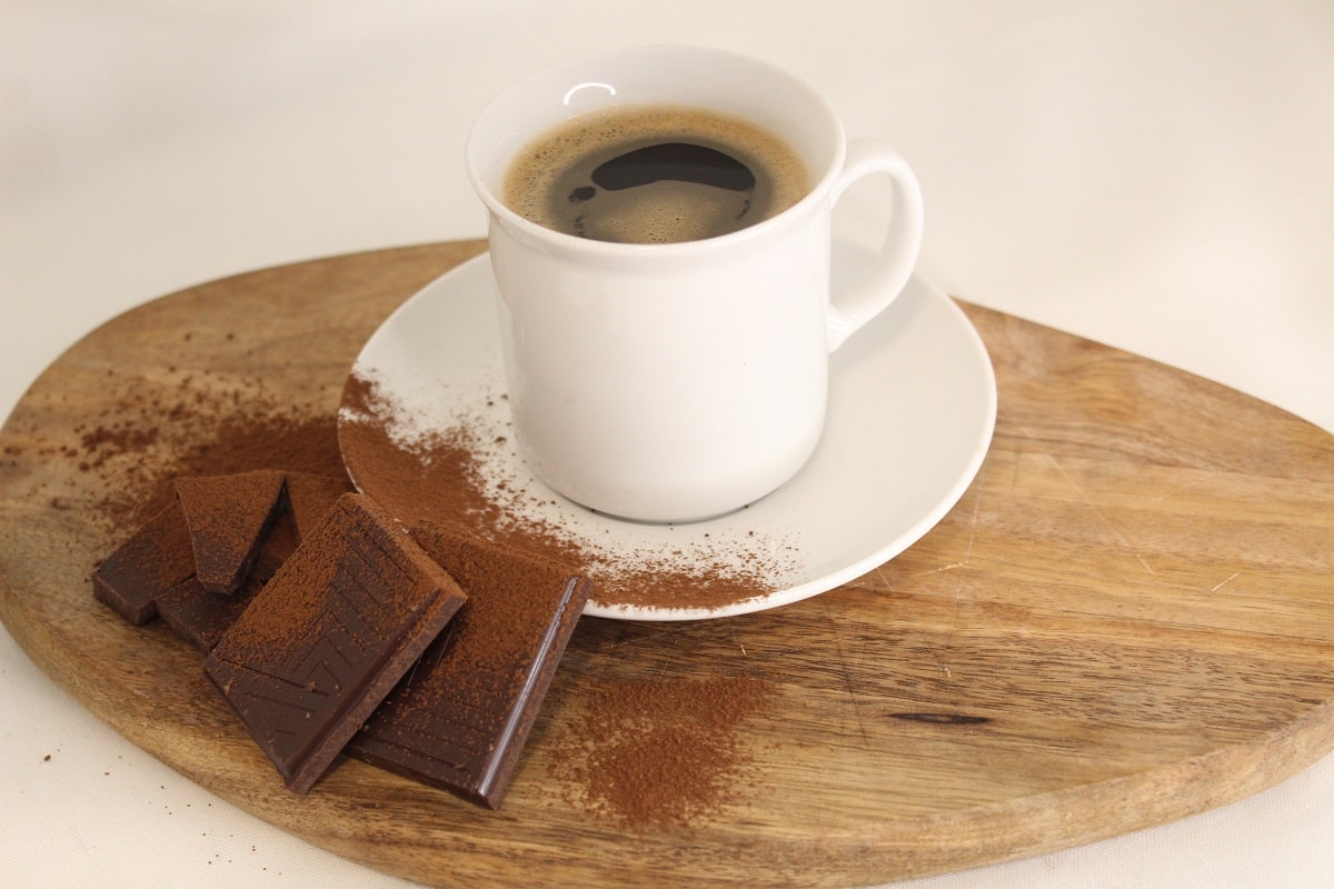 a cup of coffee and some dark chocolate with cocoa powder on it