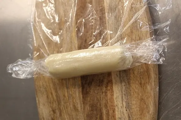a marzipan roll being tightly wrapped in cling film