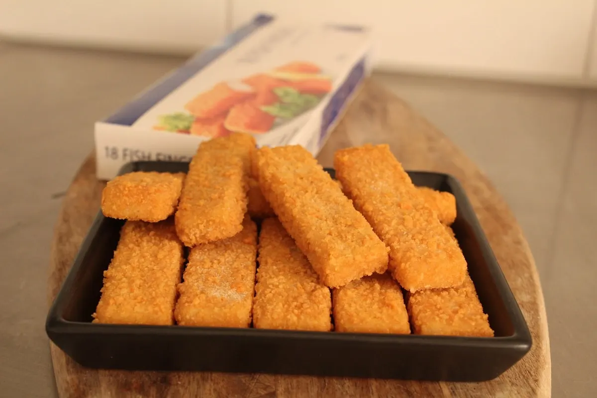 several frozen fish sticks in front of a fish stick package in the kitchen