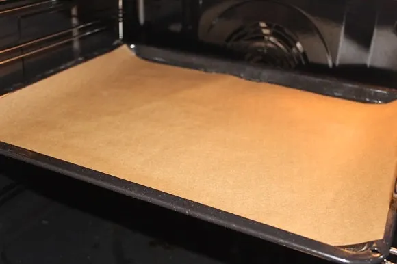 parchment paper with the right side up on a baking sheet in the oven