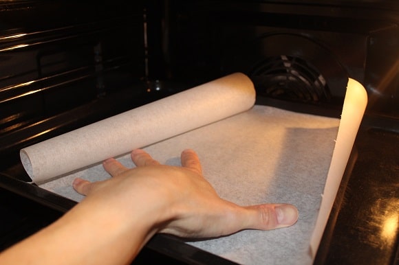 a home baker trying to flatten parchment paper on a baking sheet