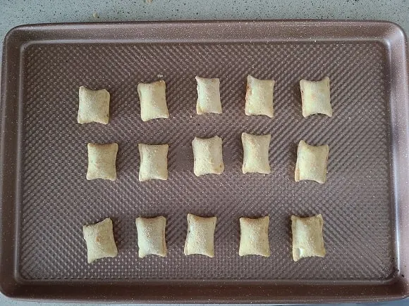 frozen pizza rolls lined up on a baking sheet ready to be put in the oven