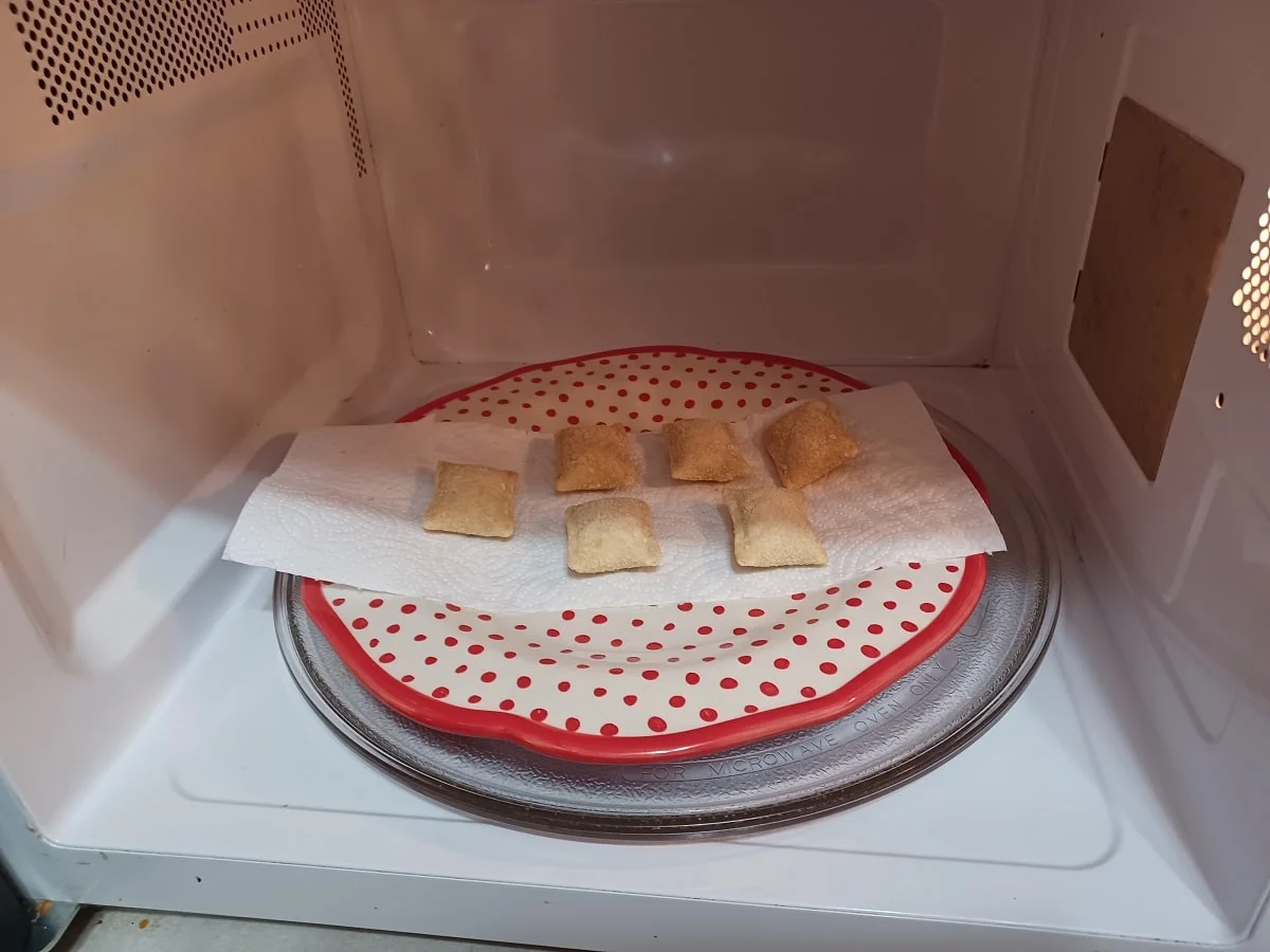 a serving of six pizza rolls on a plate in the microwave