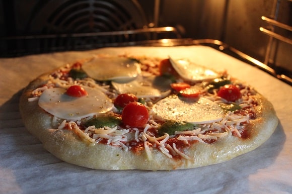 a frozen pizza baking on parchment paper directly on an oven rack