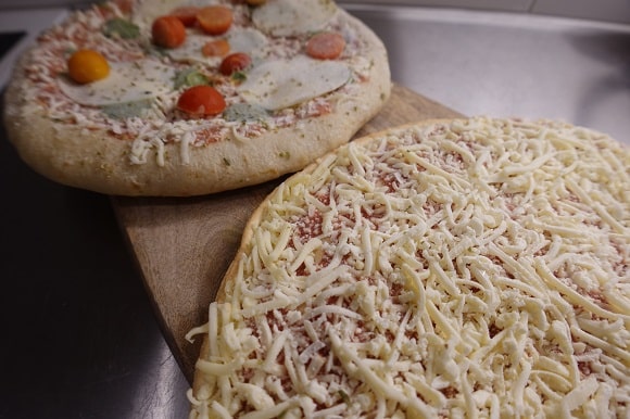 two frozen pizzas thawing at room temperature for 30 minutes in the kitchen