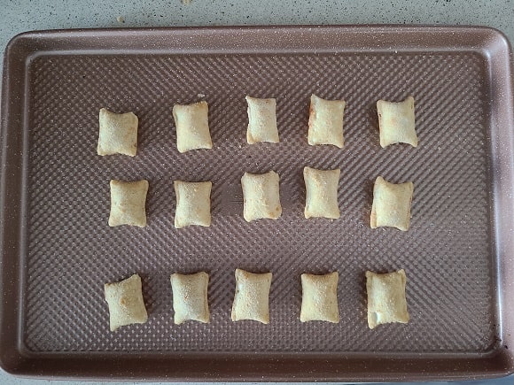 a bunch of pizza rolls on a baking sheet ready for the oven