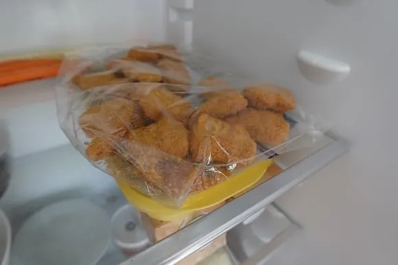 a bag of frozen chicken nuggets thawing in the fridge
