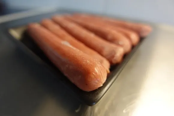 a bunch of frozen hot dogs thawing at room temperature