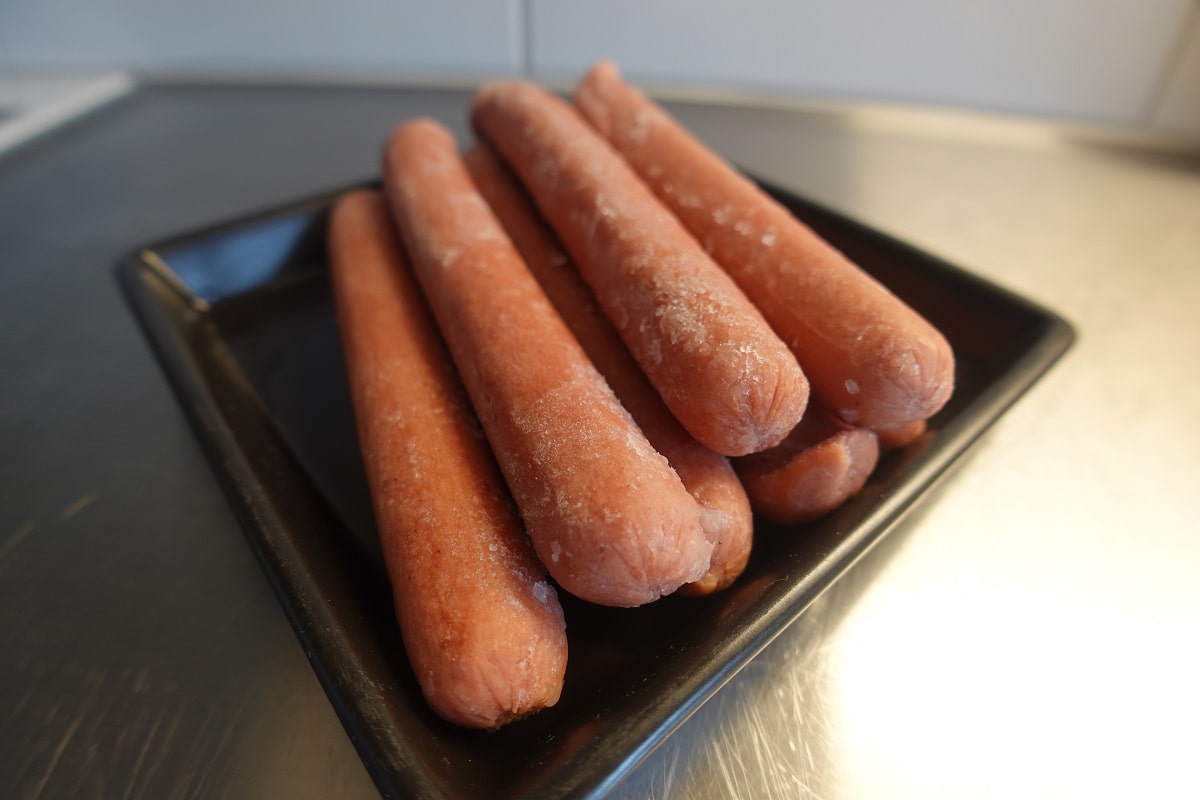 a pack of opened frozen hot dogs thawing on the kitchen counter