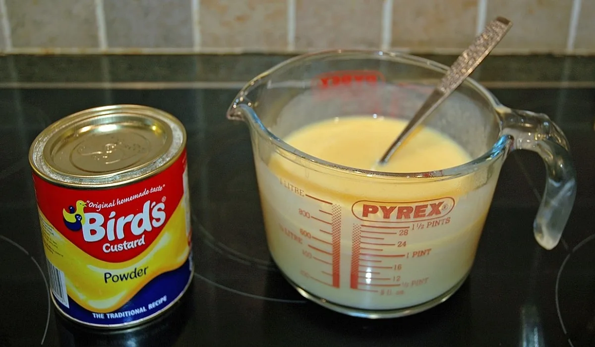 a can of bird's custard powder next to a bowl of ready custard on the stove