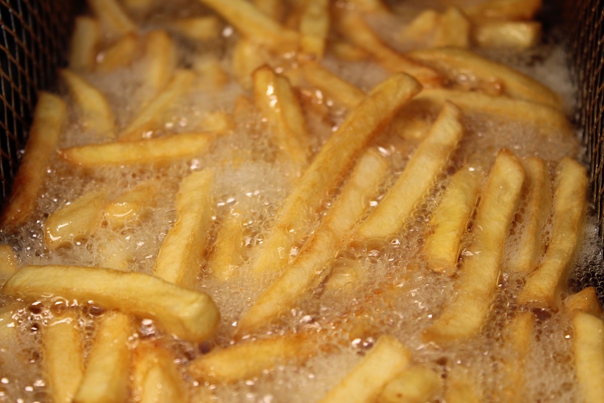a portion of frozen french fries cooking in the deep fryer